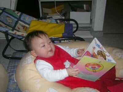 Katja sitzt im Stillkissen und hält ein Buch